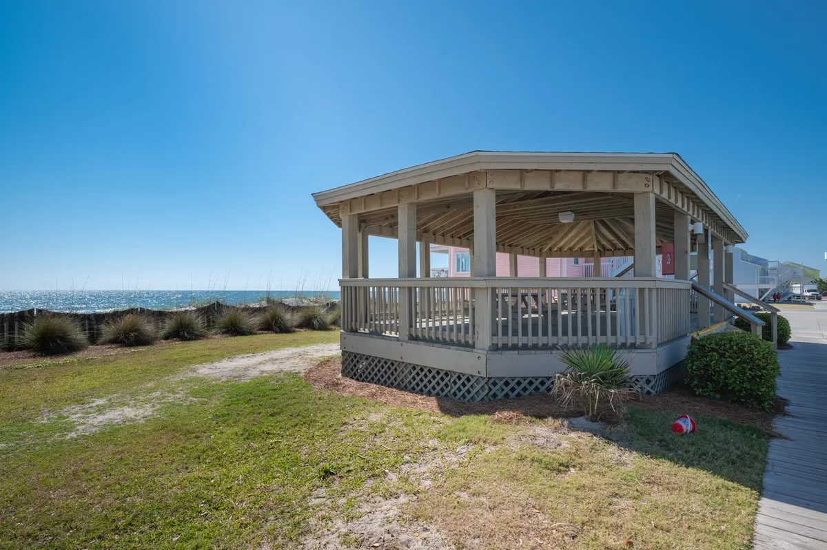 An inviting exterior scene featuring a charming gazebo overlooking the grassy area and the ocean beyond. The area is perfect for picnicking, gathering with friends, or simply enjoying the ocean breeze.